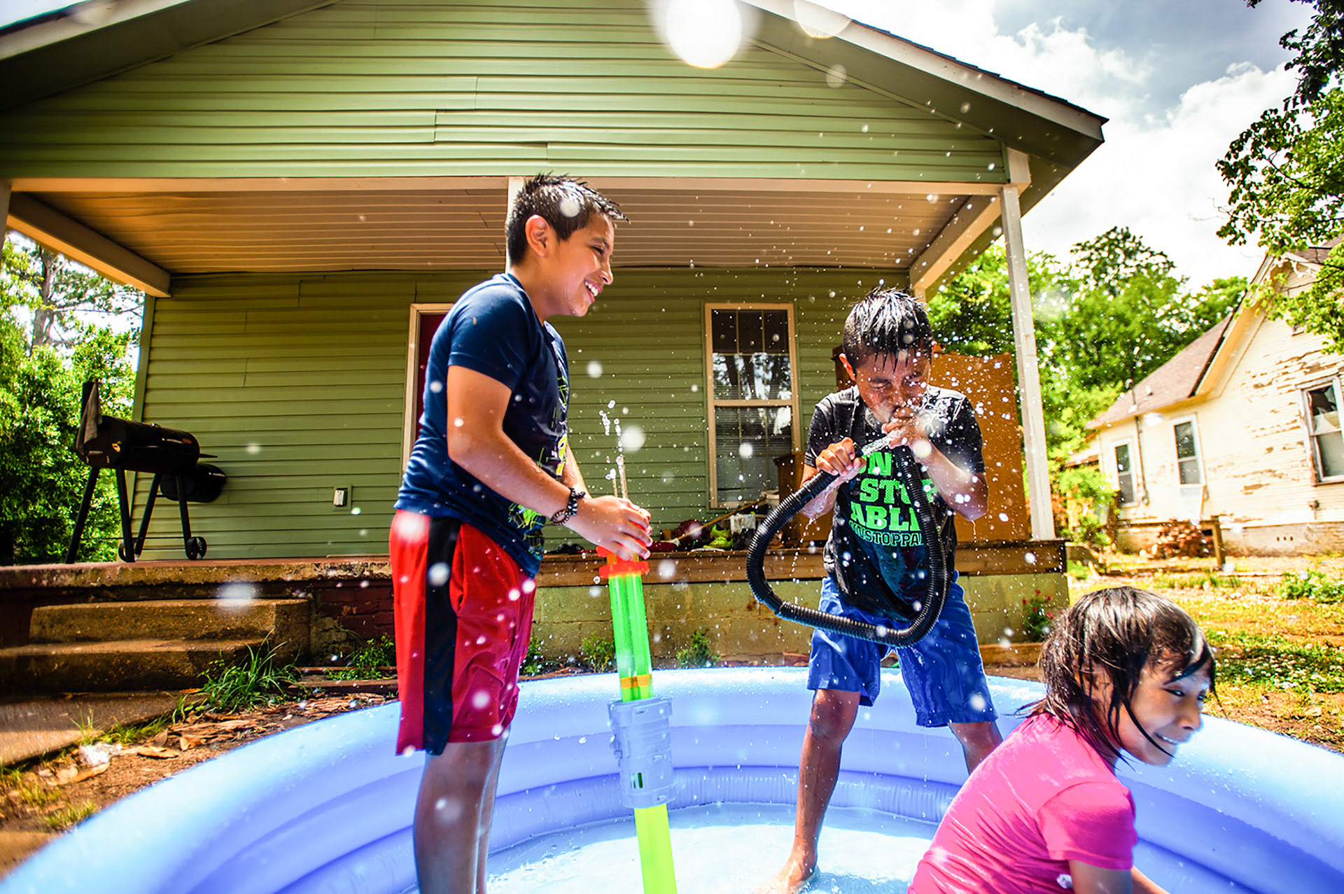Matias Matias 8, center, uses a vacuum hose to squirt water as he plays in the pool with his brother Juan, 12, left, and sister Jessica, 7, on Thursday, May 30, 2019, in Southwest Decatur, Ala.