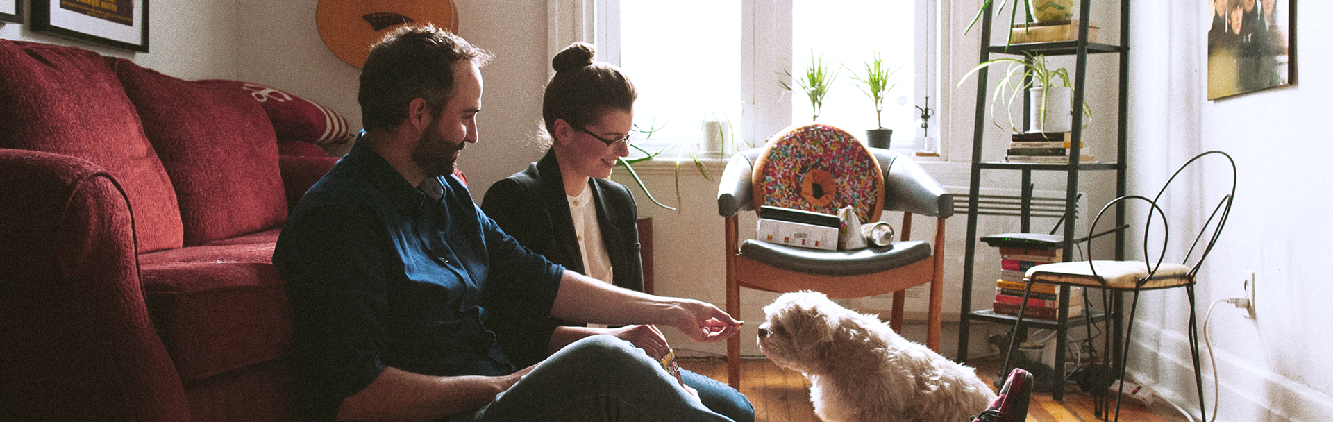 Image of Cassy and her partner offering Derp a treat in their living room