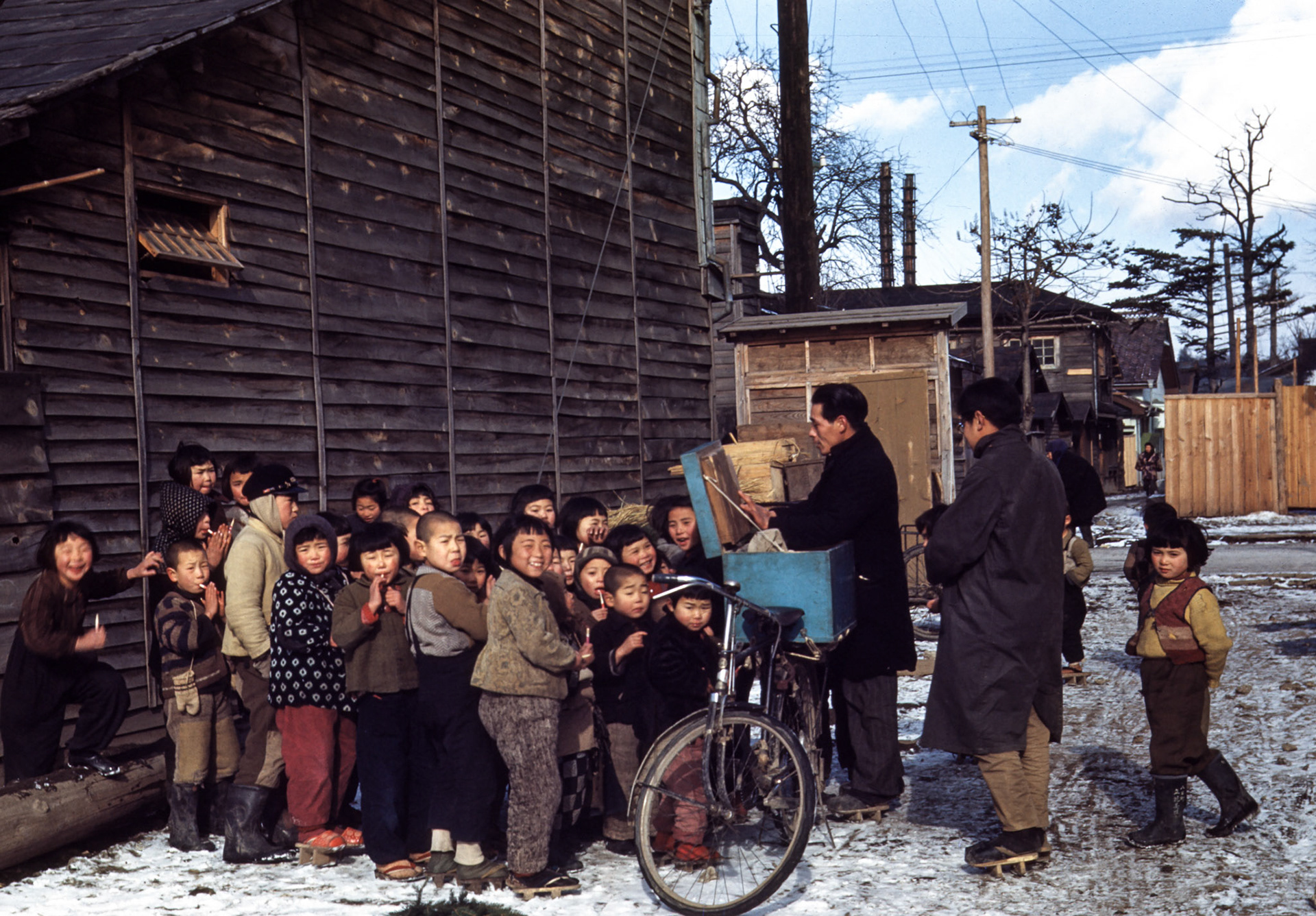 Street scene in Morioka - The man is a story teller. He is showing pictures that illustrate the story he is telling. He makes his living selling candy to the kids. Of course he doesn't tell the entire story in one day.