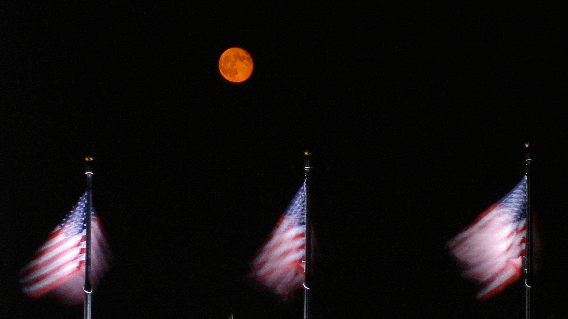 Patriotism at its finest.  Three American flags flanked by a harvest moon at the Washington Monument