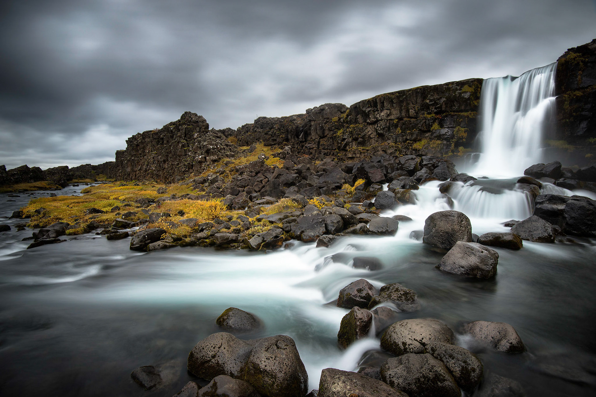 Öxarárfoss is a popular waterfall as its base is filled with black rocks located in Þingvellir National Park, Iceland.
