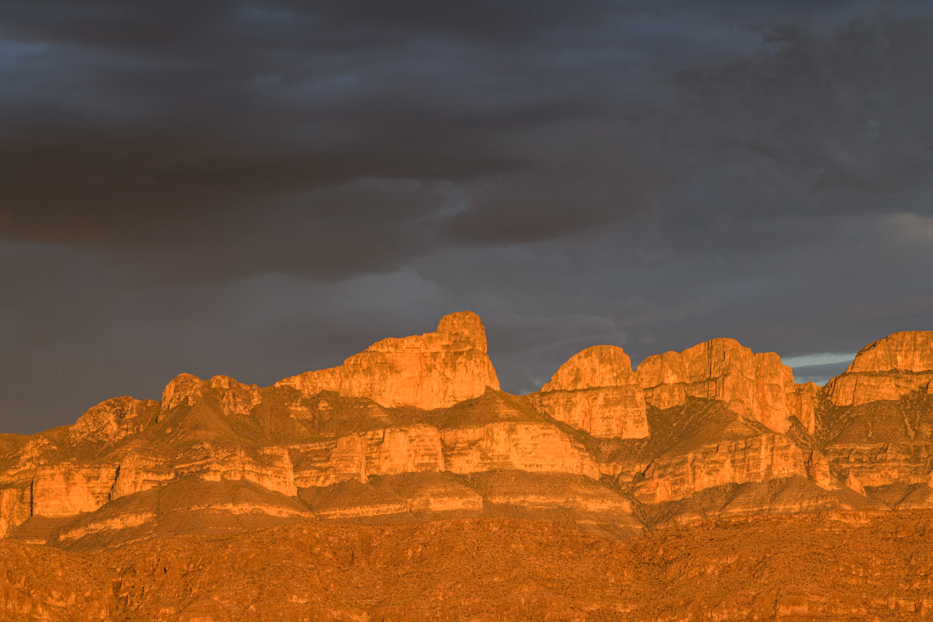 The Sierra del Carmen mountain range in Mexico illuminated at sunset with storm clouds in the background — Big Bend National Park.