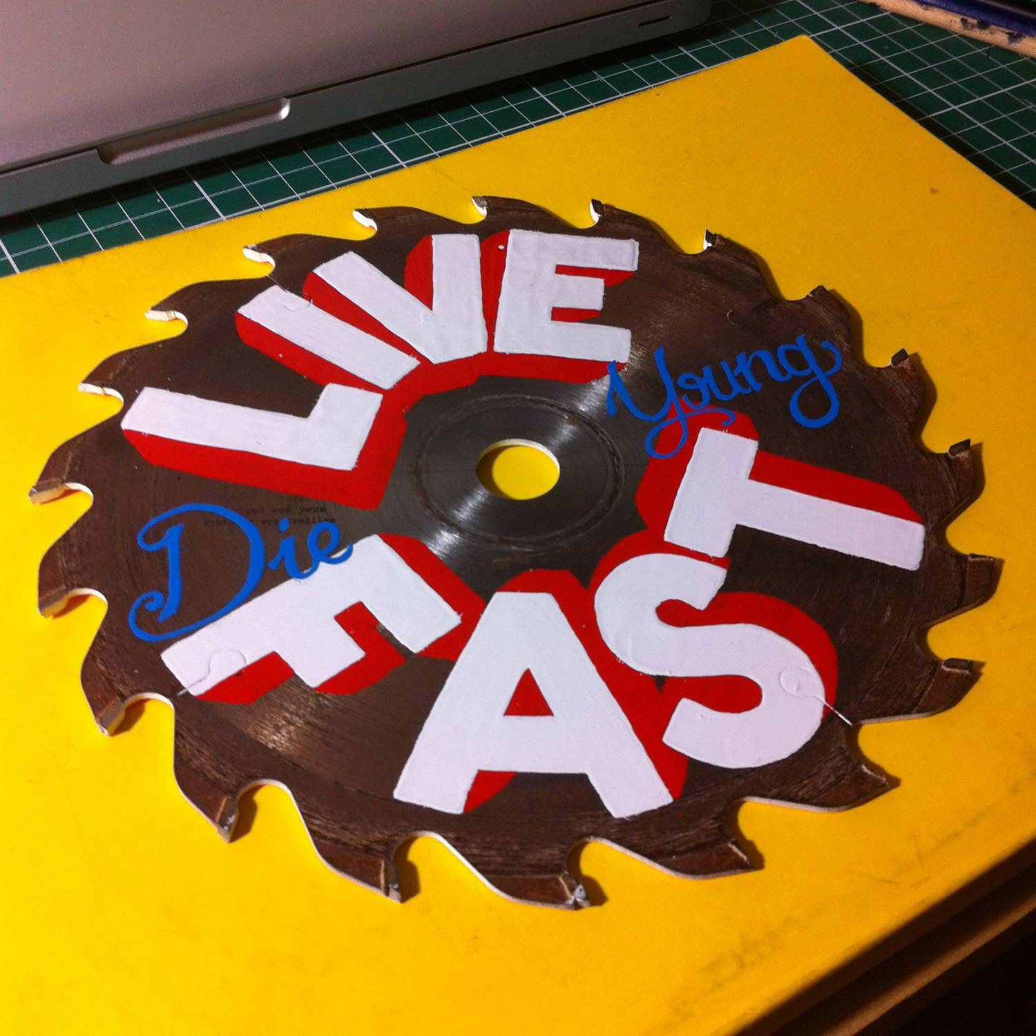 Sign-painting Live Fast Die Young sur scie circulaire
